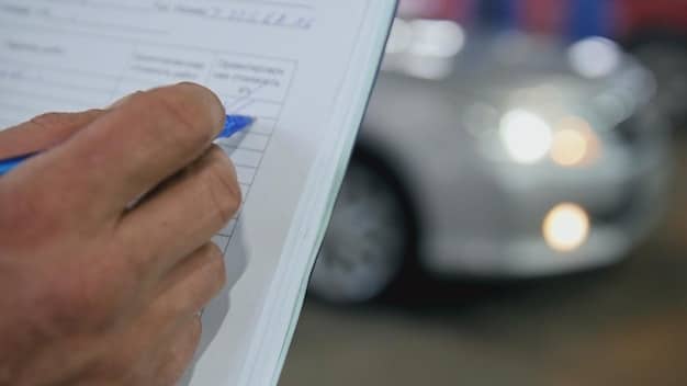 A close-up of an open auto insurance policy document, highlighting sections on liability coverage and deductible amounts. A pen is resting on the document, suggesting active review.