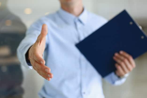 A close-up of a hand shaking over a contract, symbolizing agreement. The background is blurred, focusing attention on the handshake and the contract details.