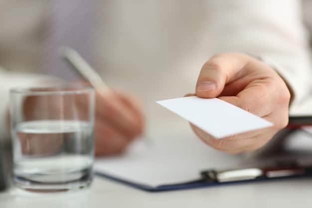 A hand holding a health insurance card, with a blurred background showing various documents related to healthcare coverage and policy details. Focus on the importance of insurance in managing healthcare costs.
