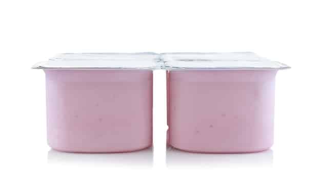 A side-by-side comparison of two nearly identical containers of yogurt, one with a popular name-brand label and the other with a store-brand label from a supermarket chain. The image highlights the minimal difference in packaging and appearance.