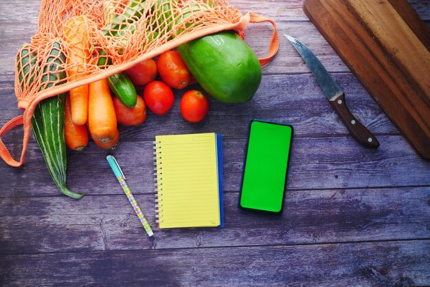 A split image showing a meticulously prepared grocery shopping list on one side and a rewards card with various coupons attached on the other.
