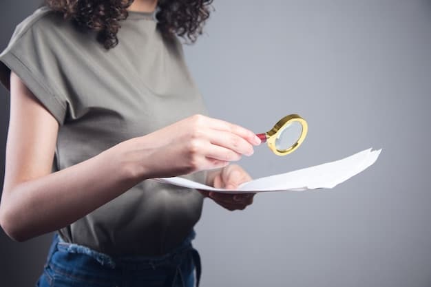 A person's hand holding a magnifying glass over a document with complex text and numbers, symbolizing detailed review and comparison of insurance policies.