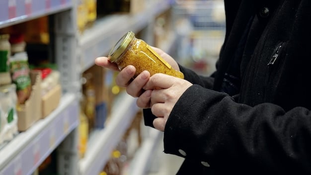 A person's hand carefully comparing unit prices on two different brands of canned beans in a brightly lit supermarket aisle, demonstrating smart consumer choices.