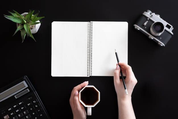 A person's hand holding a pen, poised over a financial planner or budget book with 