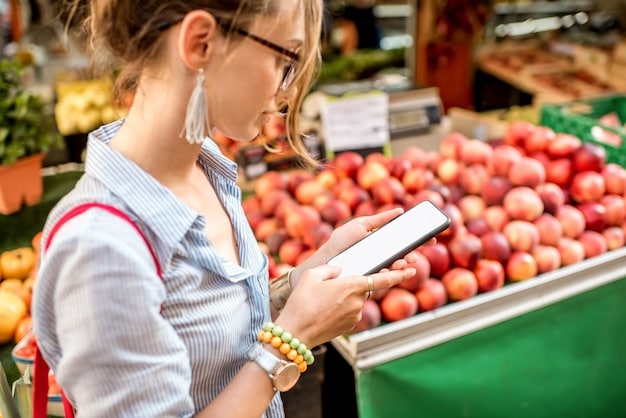A person meticulously checking prices on their phone while shopping in a grocery store, with various produce in the background.