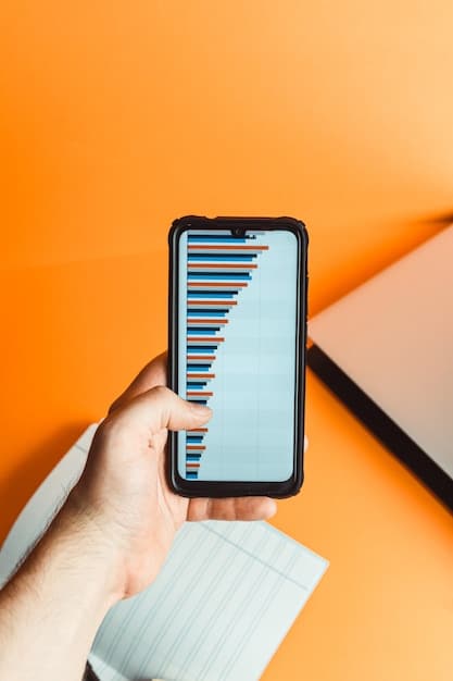 A person's hand holding a smartphone displaying a banking app's savings account balance with growing numbers, set against a backdrop of financial charts and graphs.