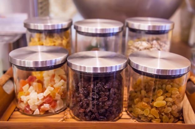 Close up of various bulk food storage containers that include grains, pasta, and nuts with labels indicating purchase dates.