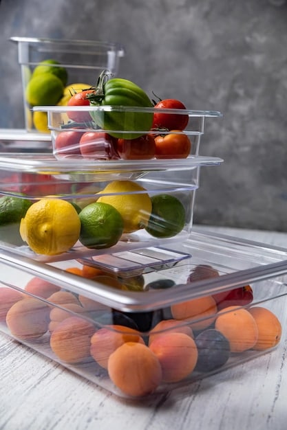 A close-up of various fruits and vegetables stored in airtight containers in a refrigerator. Some items are in crisper drawers with humidity control. The image emphasizes the importance of proper storage containers and settings to prevent spoilage and Reduce Food Waste, Save Money: Smart Grocery Storage Tips for Extending Shelf Life.