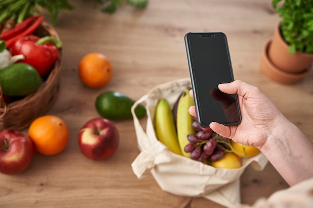 Close-up of a hand holding a smartphone, displaying a mobile app for comparing grocery prices at different stores, showcasing a digital tool for Beat Inflation at the Grocery Store: Strategies for Finding Affordable Alternatives.