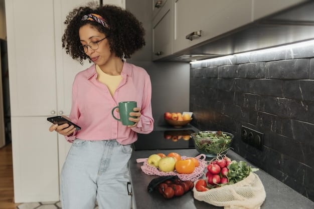 A person using a budgeting app on their smartphone while reviewing grocery receipts on a kitchen counter filled with fresh produce.