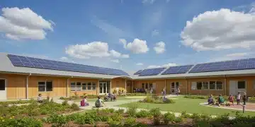 Modern school building with solar panels and green landscaping, showcasing sustainable design elements.